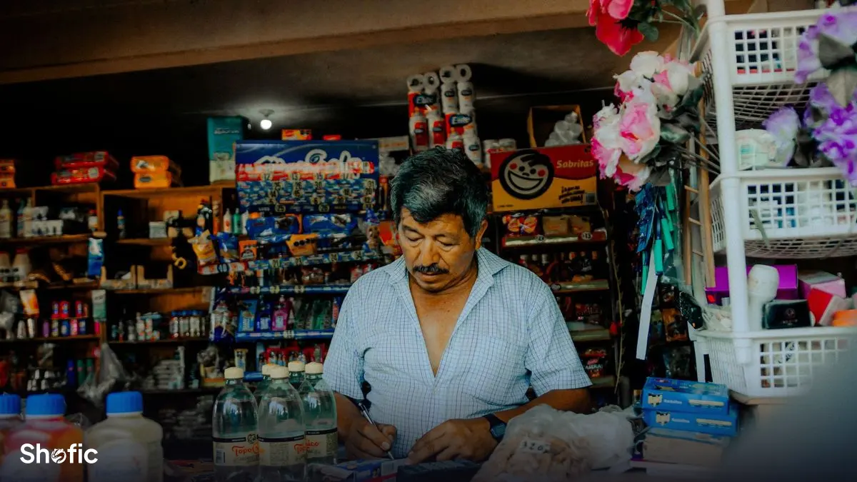 A shopkeeper checking a phone behind a counter