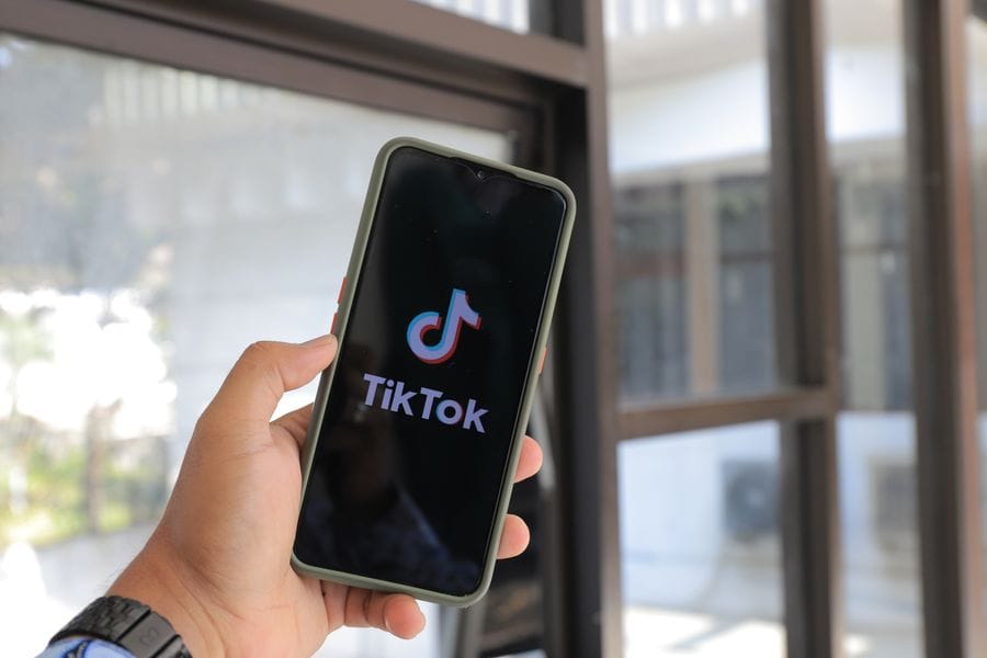 A creator reviewing TikTok video analytics on a smartphone next to a ring light